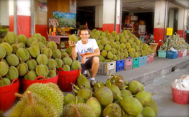 Andrew Perlot holds a durian amid dozens of the tropical fruits