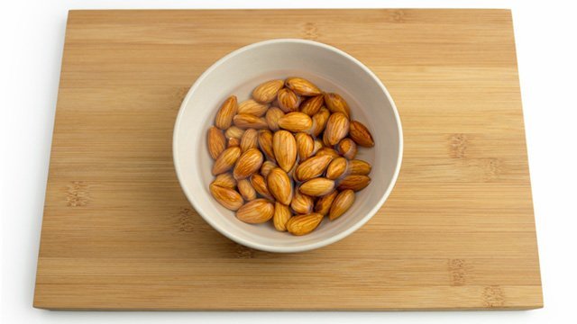 Almonds soak in water in a bowl on a wooden surface