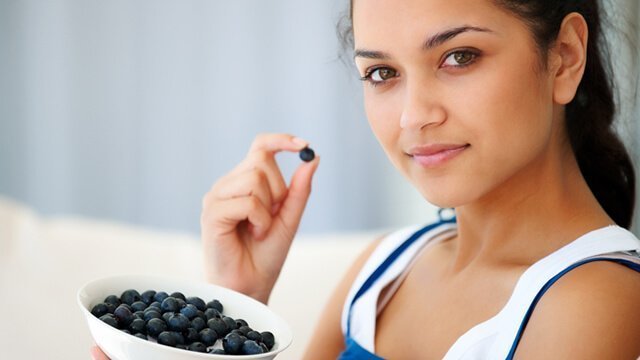 Young woman eating from a bowl of blueberries