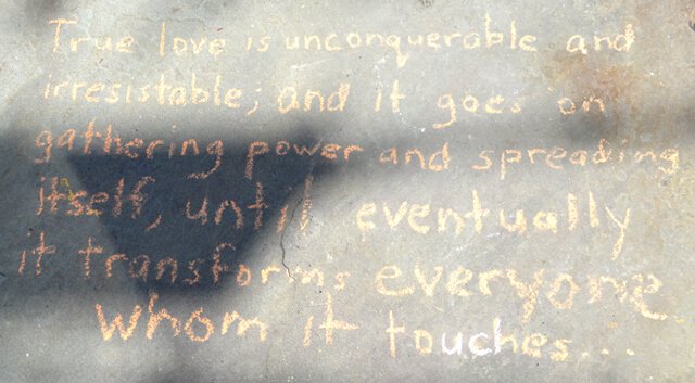 A quote is written in chalk on a walkway outside Nucleus Raw Foods
