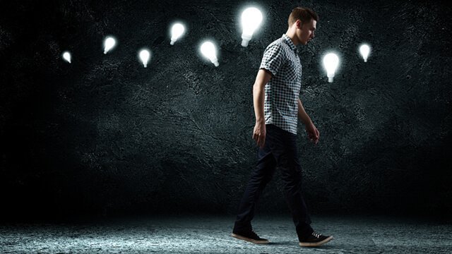 Man walking in the dark with lightbulbs guiding his way