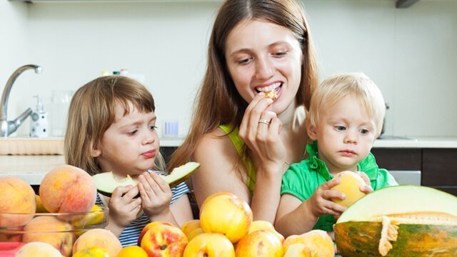 Family eating fruit in a kitchen
