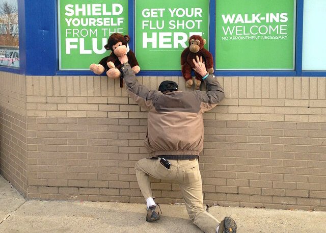 Arnold Kauffman holds stuffed monkeys over a vaccination sign
