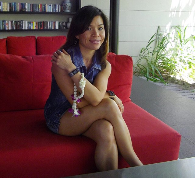Mewsum Wong is photographed while seated on a red couch