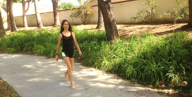 Alicia Grant walks barefoot outside along a sidewalk