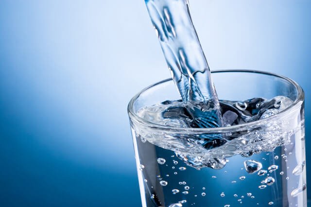 Pouring water into a glass on a blue background