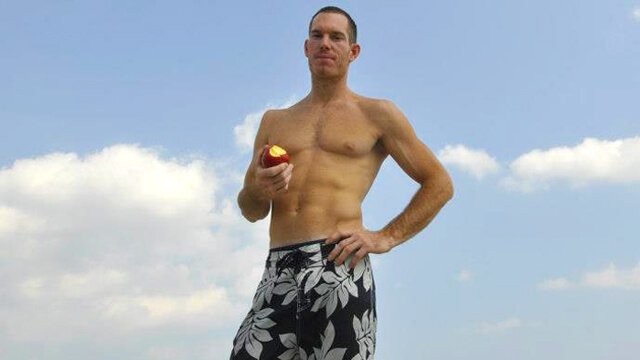 Korey Constable eats an apple with the sky as a background