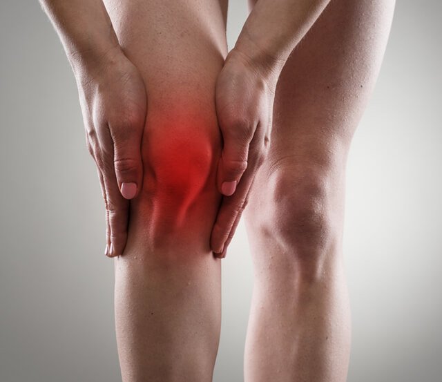 Woman touches her inflamed right knee
