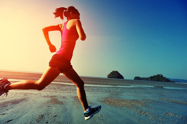 Woman runs along a beach at sunrise