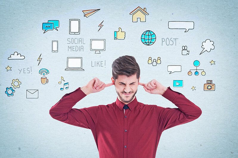 Stressed businessman covers his ears with social media icons around him